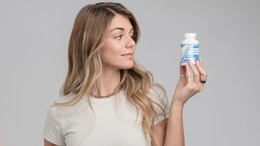 Julia, a former college track athlete, holding K3 Nutriments Omega-3 Fish Oil—supporting recovery, joint health, and hormone balance for women who train.